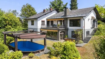 Großzügiges Einfamilienhaus mit Garten, Pool und Balkon in grüner Umgebung.