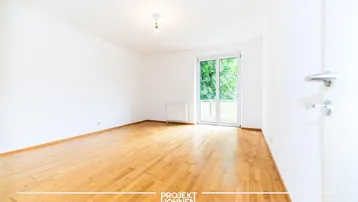 Geräumiges Wohnzimmer mit Parkettboden und Zugang zu einem französischen Balkon.