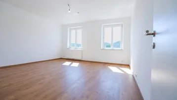 Geräumiger, heller Raum mit Laminatboden und zwei Fenstern, die viel Tageslicht hereinlassen.