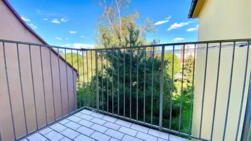 Balkon mit Fliesenboden und Metallgeländer, bietet einen grünen Ausblick auf die Umgebung.