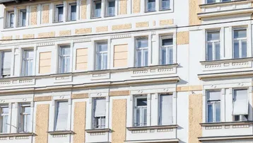Detailansicht der historischen Fassade mit vielen Fenstern und dekorativen Elementen unter blauem Himmel.