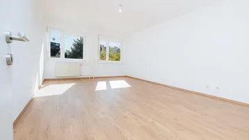 Heller, leerer Raum mit Parkettboden und zwei Fenstern, ideal als Wohn- oder Schlafzimmer.