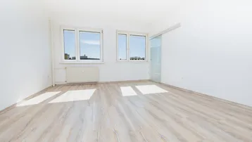 Heller, leerer Raum mit großen Fenstern und modernem Laminatboden, ideal als Wohn- oder Schlafzimmer.
