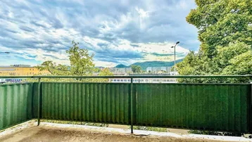 Balkon mit grüner Brüstung und weitem Blick auf die umliegende Landschaft und Berge.