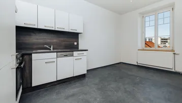 Helle Küche mit weißen Schränken, dunkler Arbeitsplatte und Blick auf die Stadt.