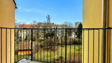 Geräumiger Balkon mit Fliesenboden und Blick ins Grüne sowie auf umliegende Gebäude.