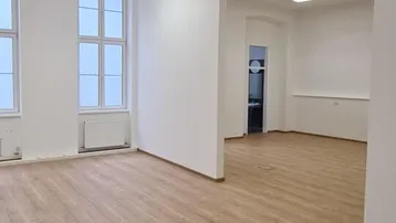 Geräumiger, heller Büroraum mit großen Fenstern und modernem Laminatboden.