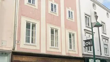 Historische Fassade eines Gebäudes mit Geschäften im Erdgeschoss und Wohnungen in den oberen Etagen.