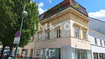 Historisches Gebäude mit aufwendiger Fassadenverzierung und Dachterrasse in städtischer Umgebung.