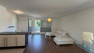 Geräumiger Wohnbereich mit Zugang zum Balkon und Blick ins Grüne.