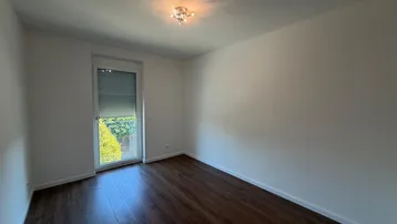 Ruhiges Schlafzimmer mit Laminatboden und Zugang zu einem französischen Balkon.