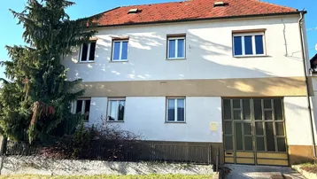 Mehrstöckiges Wohnhaus mit heller Fassade, roten Dachziegeln und integrierter Garage.