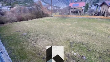 Weitläufiges Grundstück mit grüner Wiese und beeindruckendem Blick auf die umliegenden Berge.