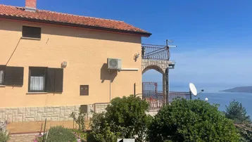 Hausfassade mit Balkon und Klimaanlage, bietet einen weiten Blick auf das Meer und die Küste.
