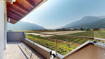 Großer Balkon mit weitem Blick über Felder und die umliegende Berglandschaft.