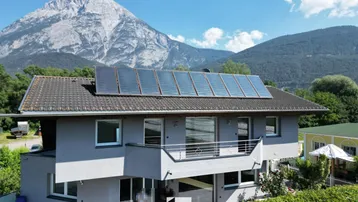 Hausfassade mit Solaranlage auf dem Dach und beeindruckendem Bergblick.