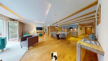 Geräumiger offener Wohn- und Essbereich mit Holzboden, moderner Einrichtung und Zugang zum Balkon mit Bergblick.