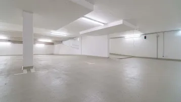 Weitläufige und helle Tiefgarage mit sauberem Betonboden und guter Beleuchtung.