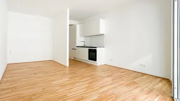 Heller Wohnbereich mit modernem Eichenparkett und integrierter Küchenzeile in minimalistischem Design.