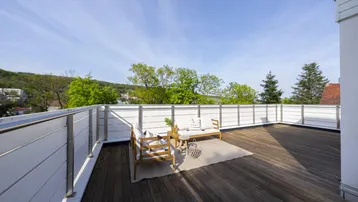 Große Dachterrasse mit Holzbelag, bequemen Gartenmöbeln und weitem Blick ins Grüne.