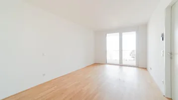 Lichtdurchfluteter Raum mit Holzboden und französischem Balkon, bietet viel natürliches Licht.