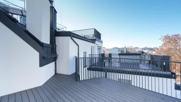 Geräumige Dachterrasse mit modernem Holzverbundboden und Blick über die Stadt.