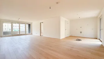 Geräumiger, heller Wohnbereich mit großen Fenstern und Zugang zu einem Balkon oder einer Terrasse.