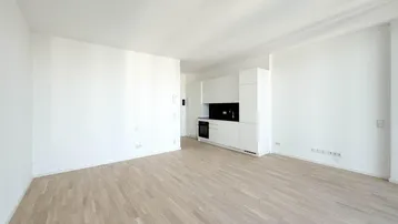 Heller Wohnbereich mit modernem Parkettboden und integrierter, minimalistischer Küchenzeile.