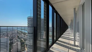 Lange Loggia mit atemberaubendem Blick auf die Stadt und den Fluss, umgeben von modernen Hochhäusern.