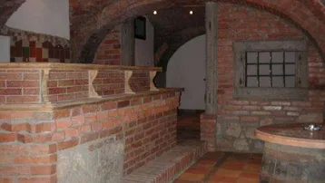 Rustikaler Kellerraum mit Ziegelgewölbe, Terrakottaboden und einer gemauerten Theke, ideal für Weinlagerung oder gesellige Runden.