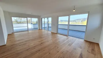 Helles, geräumiges Wohnzimmer mit neuem Parkettboden und Zugang zu einer großen Terrasse.