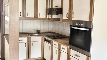 Kleine Küche mit Holzfronten, Einbaugeräten und Linoleumboden in traditionellem Stil.