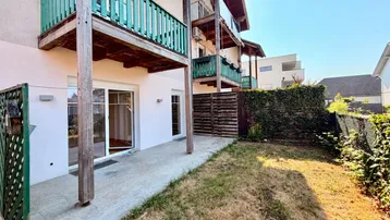Außenansicht des Gebäudes mit mehreren Balkonen, einer Terrasse und einem gepflegten Gartenbereich.