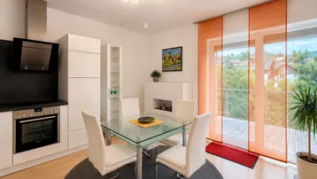 Moderne offene Küche mit weißen Schränken und Essbereich, direktem Zugang zum Balkon und schöner Aussicht.