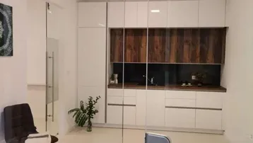 Moderne Küchenzeile mit weißen Hochglanzschränken, Holzakzenten und Glaswänden in einem hellen Raum.