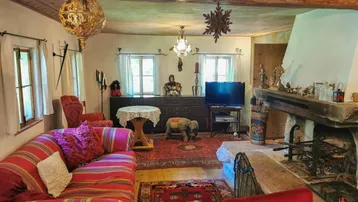 Rustikales Wohnzimmer mit großem Steinkamin, Holzbalken und traditioneller Einrichtung in warmen Farben.
