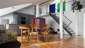 Geräumiger offener Wohn- und Essbereich mit Holzboden, moderner Küche und Galerie.
