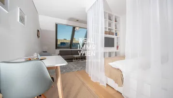 Helles Studio-Apartment mit Essbereich, Wohnbereich und Schlafbereich unter Dachschrägenfenstern.