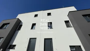 Moderne Neubaufassade in Weiß und Grau mit klaren Linien und mehreren Fenstern.