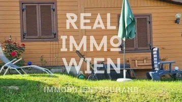 Rustikales Holzhaus mit grüner Rasenfläche und gemütlichem Sitzbereich im Freien.