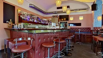 Geräumige Bar mit langer Theke, bequemen Barhockern und Spiegelwand, ideal für Gastronomiebetriebe.