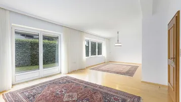 Helles Wohnzimmer mit Parkettboden, großen Fenstern und Zugang zum Gartenbereich.