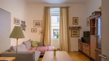 Helles Wohnzimmer mit Fischgrätparkett, beigem Sofa und Blick nach draußen.