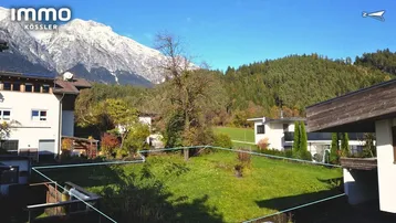 Grünes Grundstück mit altem Baumbestand und beeindruckendem Bergblick im Hintergrund.