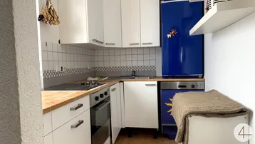 Funktionale Küche mit weißen Schränken, Holzarbeitsplatte und blauen Akzenten.