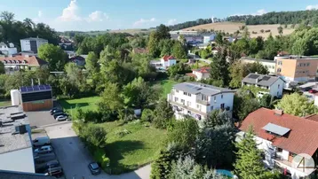 Luftaufnahme des modernen Gebäudes in einer grünen, ländlichen Umgebung mit Photovoltaikanlage auf dem Dach.