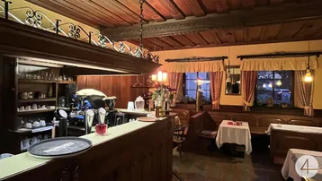 Traditioneller Gastraum mit Holzbalkendecke, gemütlichen Sitzecken und einer gut ausgestatteten Bar.