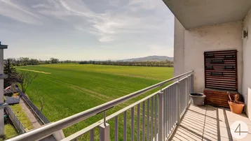 Balkon mit weitem Blick über grüne Felder und sanfte Hügel, perfekt zum Entspannen im Freien.