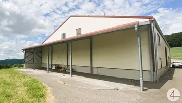 Seitenansicht eines großen Industriegebäudes mit überdachtem Bereich und angrenzender Zufahrt.