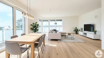 Helles Wohn- und Esszimmer mit großen Fenstern, Holzboden und Zugang zum Balkon.